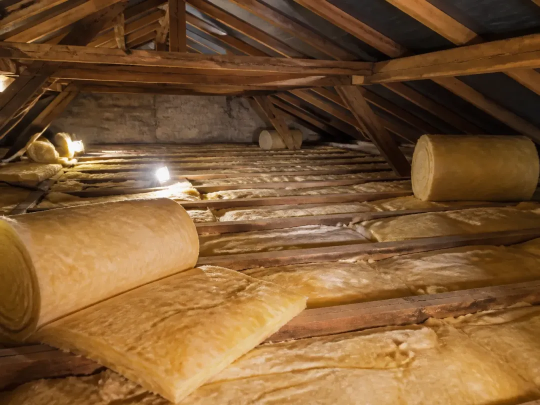 Rouleaux de laine minérale déroulés entre les solives de combles perdus