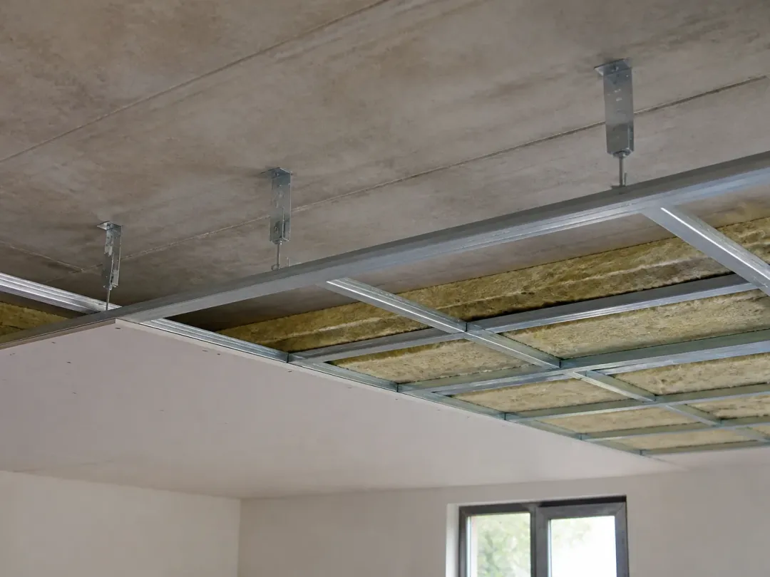 Ossature métallique de faux plafond fixée par des suspentes, laine minérale posée entre les fourrures