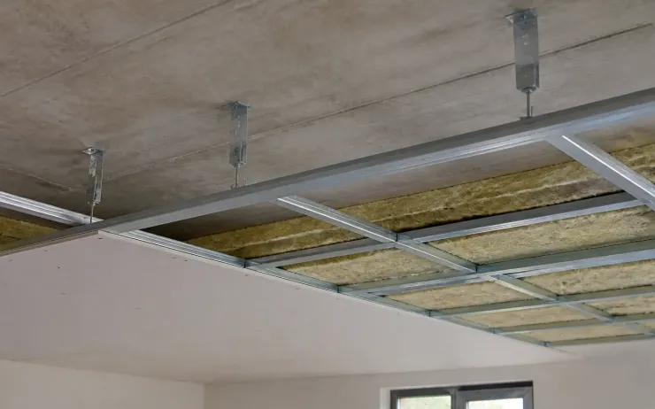 Ossature métallique de faux plafond fixée par des suspentes, laine minérale posée entre les fourrures